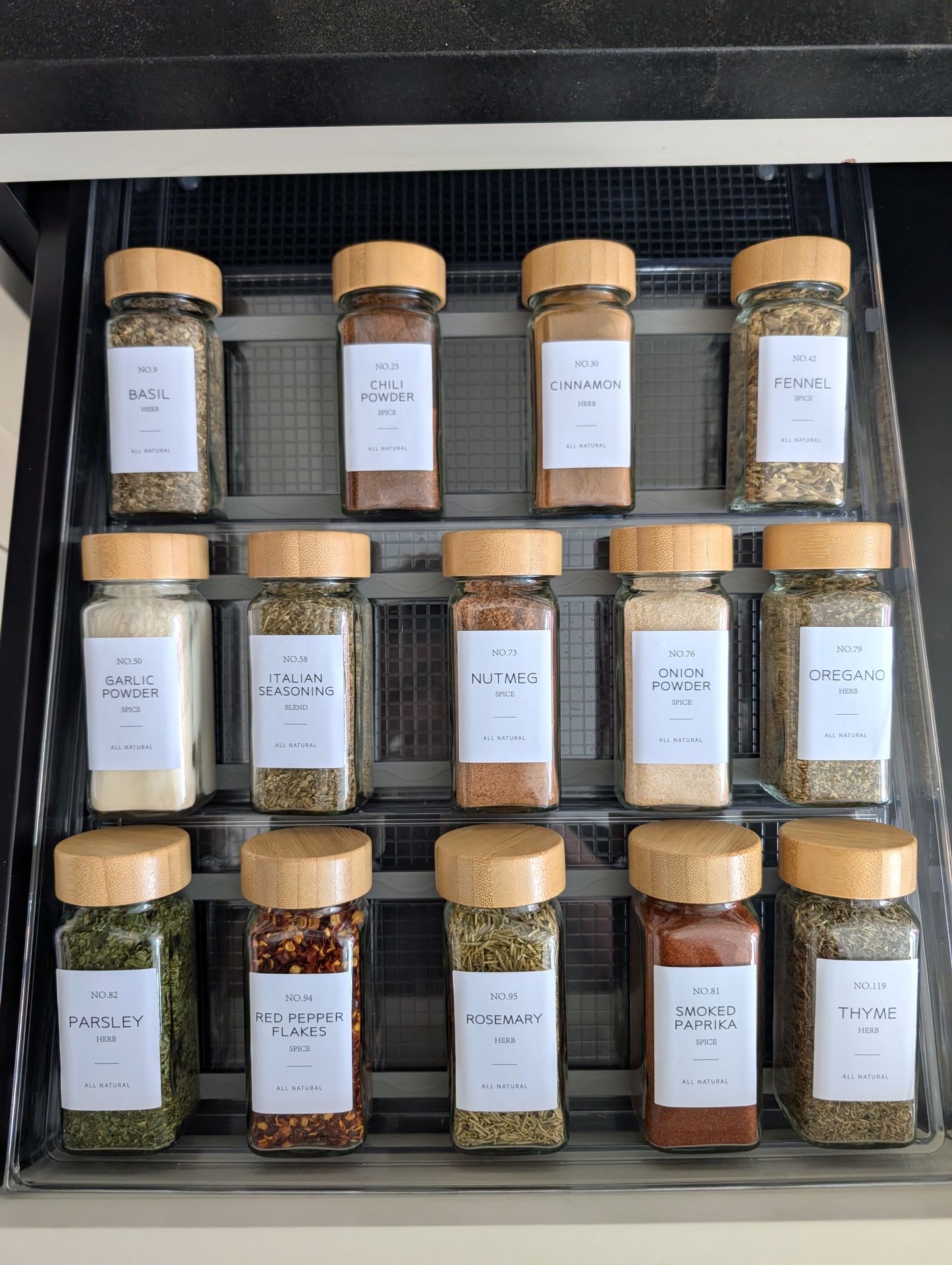 Perfectly organized spice drawer with labeled glass jars